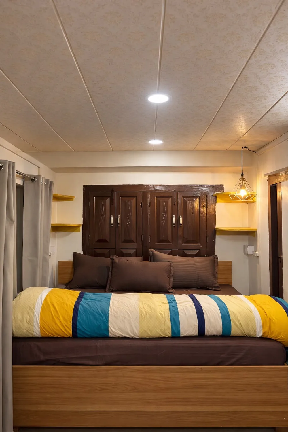 Cozy king bedroom with carved wooden headboard at Haus of Shizu homestay in Kasar Devi, Almora